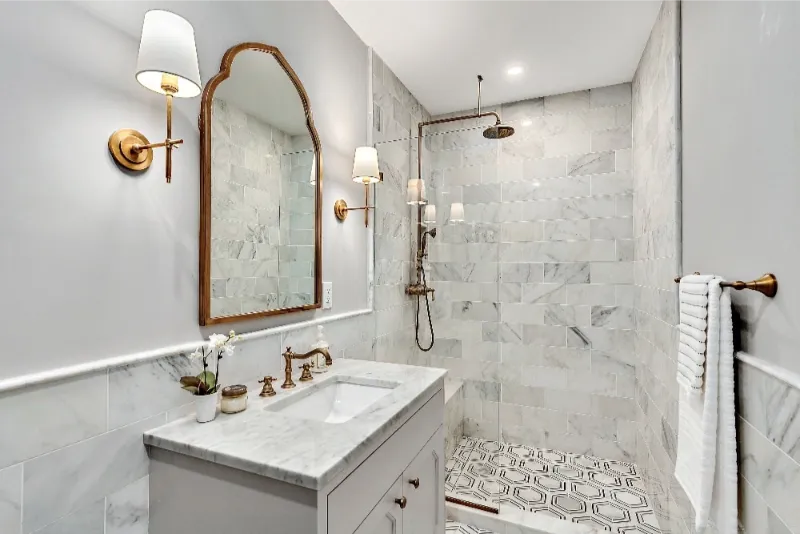 small bathroom with a curved mirror and gold accents