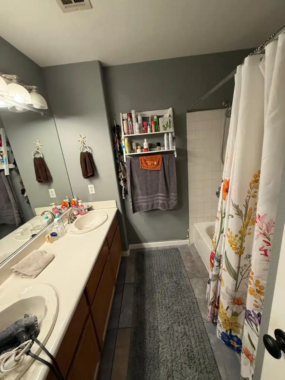 Spare bathroom before the remodel with double sink vanity, gray walls and a tub behind a shower curtain
