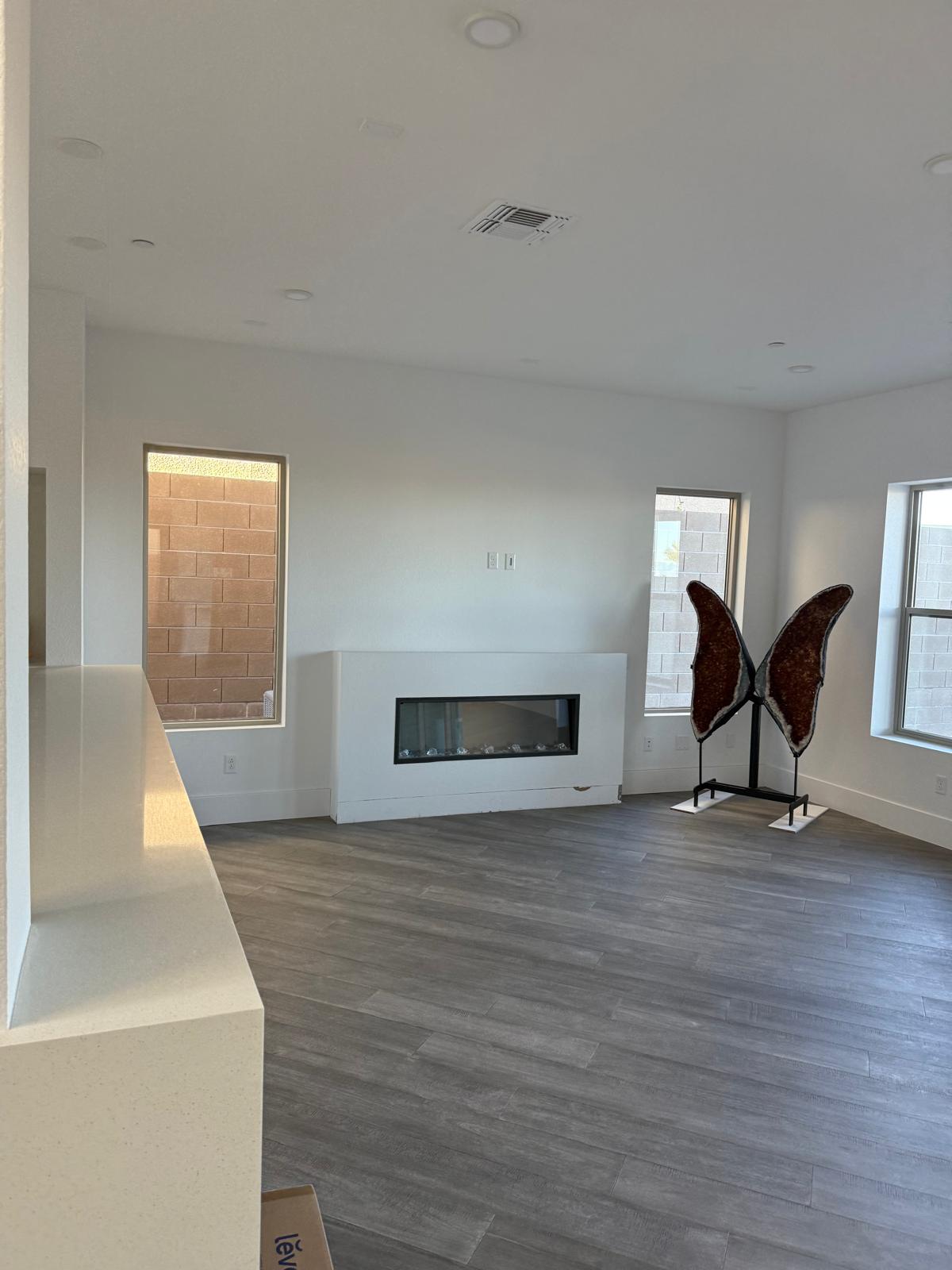 Living room with freshly painted white walls, a linear fireplace in a clean white surround and gray wood look plank floor