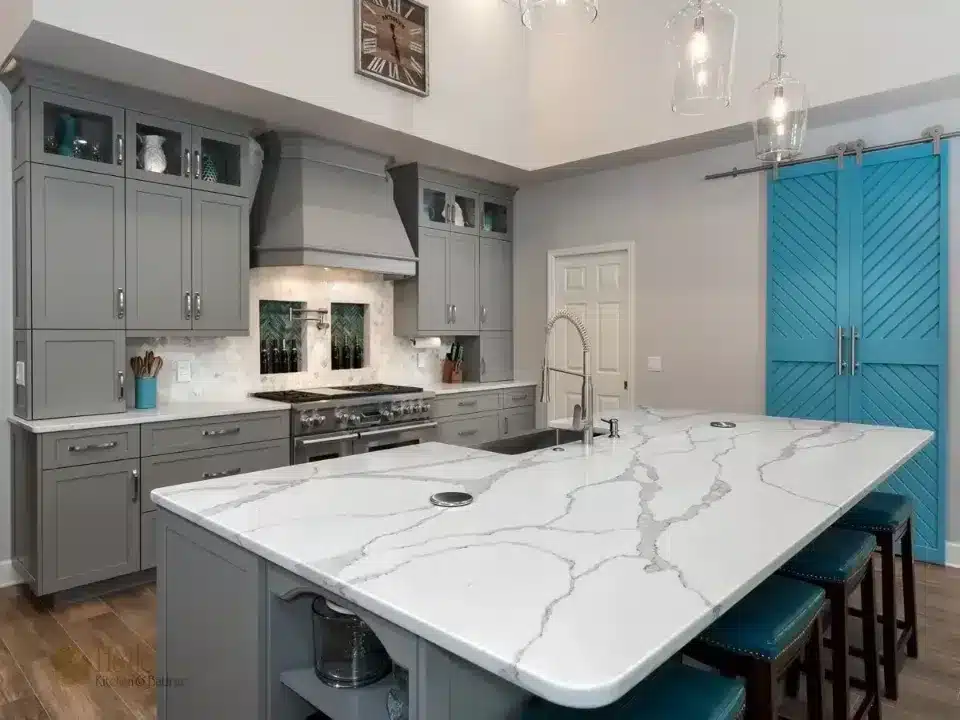 Modern kitchen with gray cabinets, marble island, turquoise barn doors, and stainless steel appliances