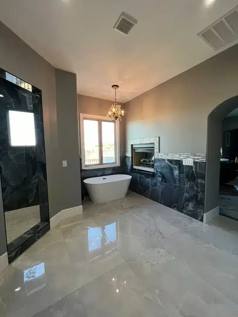 Master bathroom with freestanding soaking tub, dark marble walls, light marble floors, and built-in fireplace