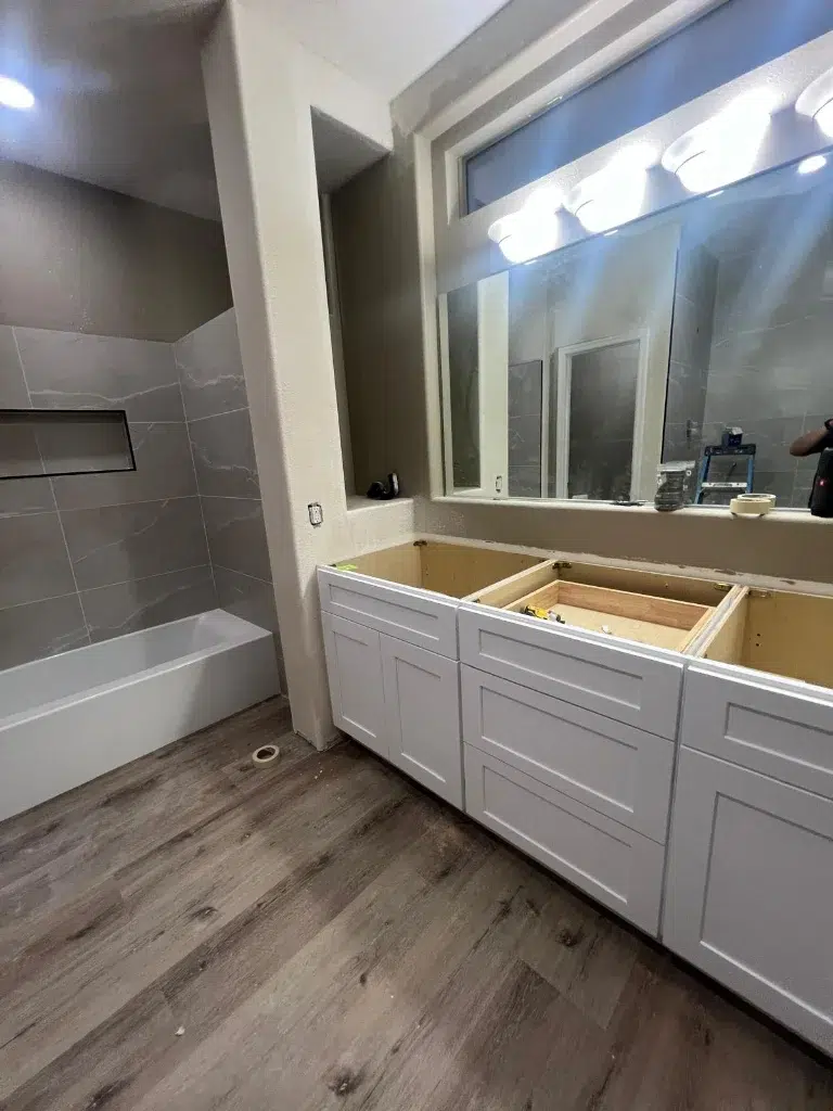 Kitchen remodel in progress with removed base cabinets, granite countertops, and gray tile flooring.