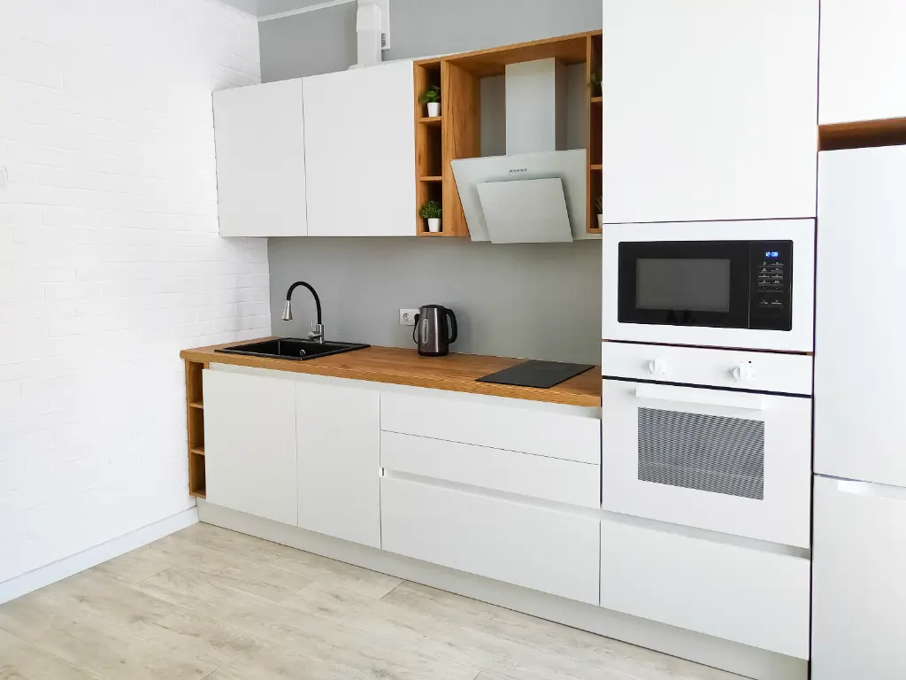 Contemporary kitchen with white cabinetry, wood countertop, built-in oven, microwave, and open wood shelving