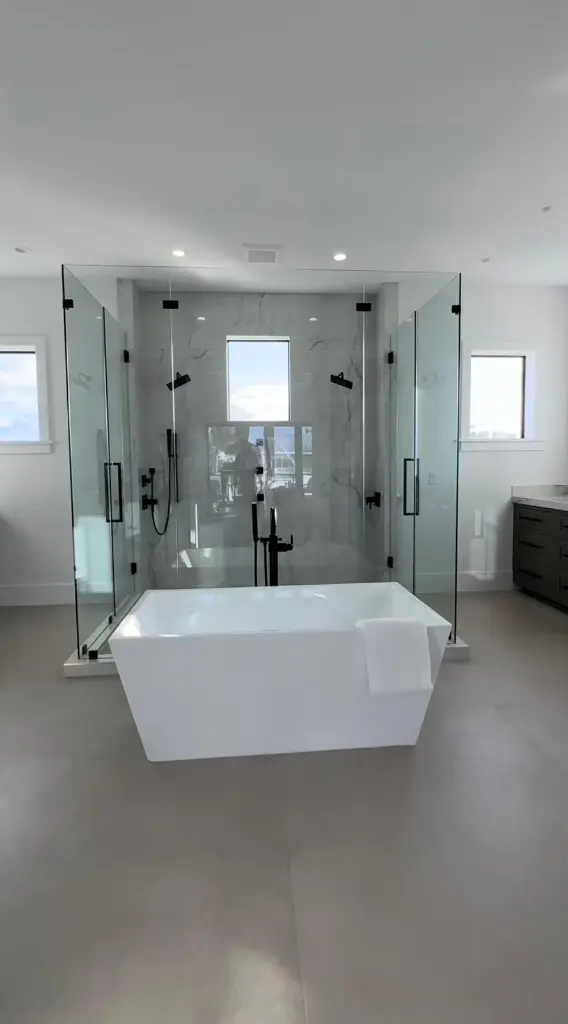 Luxury bathroom featuring a freestanding tub and dual glass showers installed over heated bathroom floors