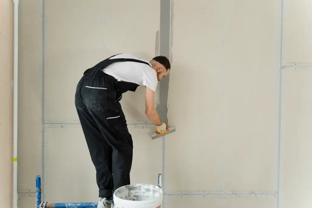 Worker smoothing joint compound along drywall seams during interior wall finishing work